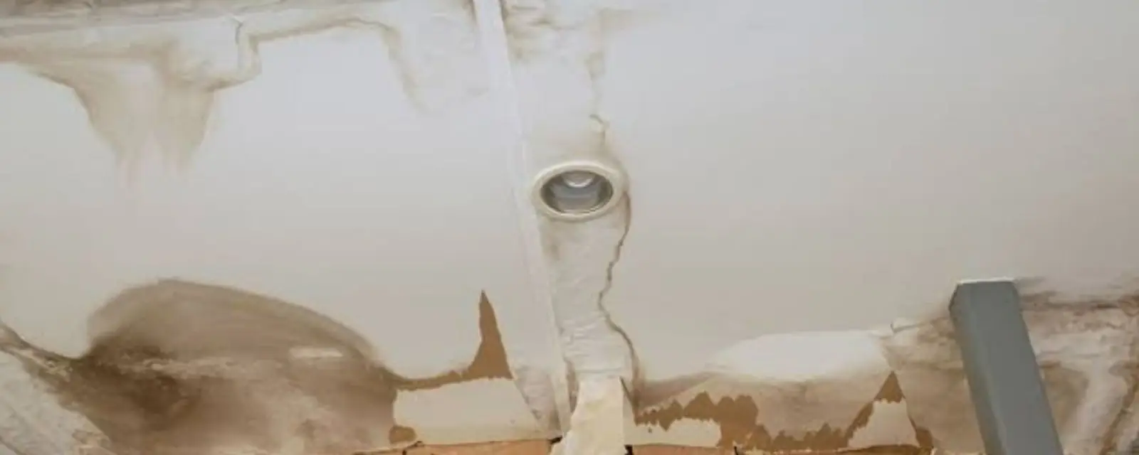Water stained ceiling with peeling paint around a light fixture