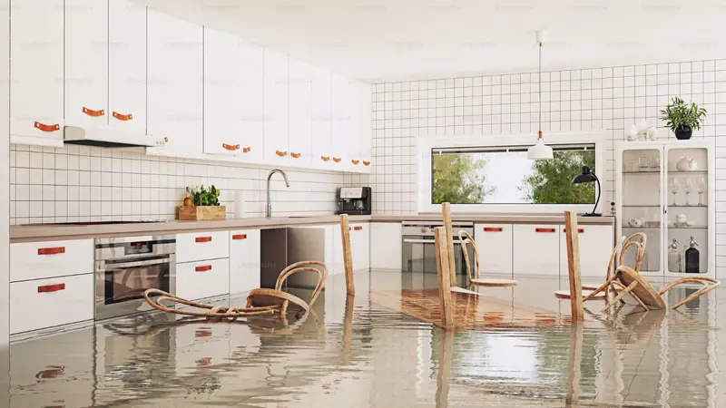 Apartment style white kitchen with an overturned chair and water on the floor